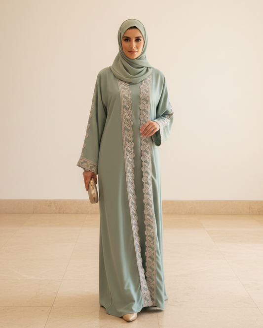Woman wearing a light blue abaya with lace details in a minimal indoor setting